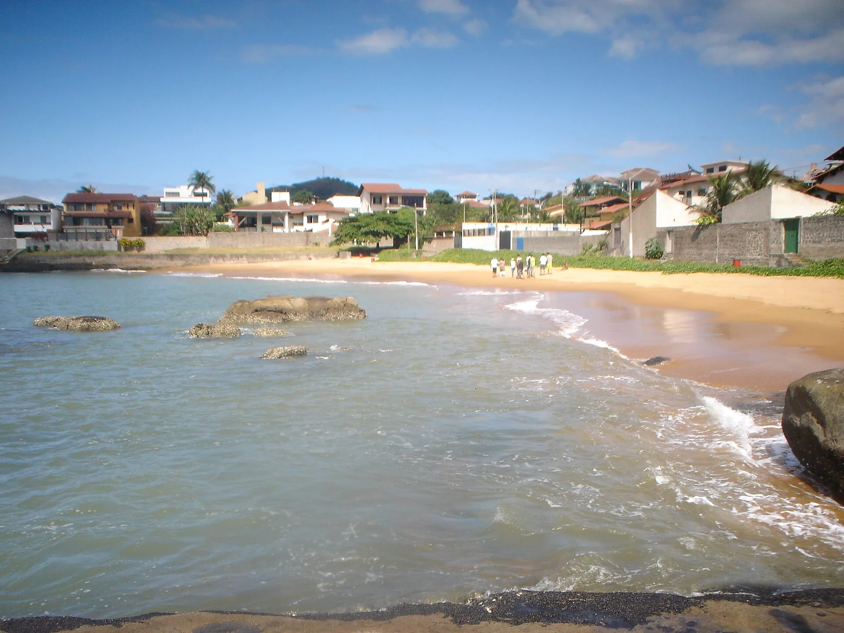 Praia de Guarapari com faixa de areia, mar e formações rochosas
